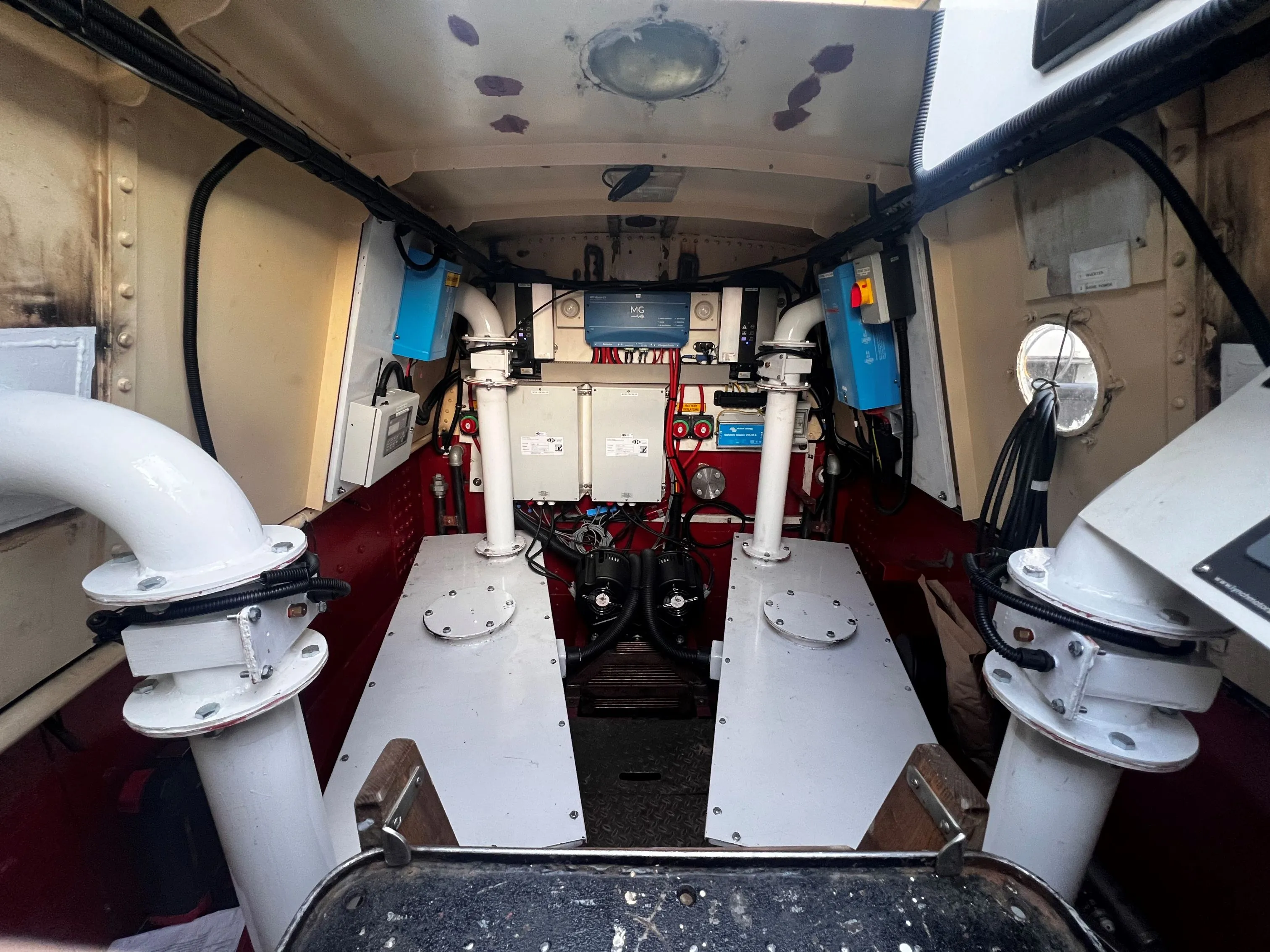 Interior of a boat engine room showing mechanical and electrical equipment, piping, and control panels mounted on walls.